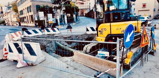 La voragine nell'asfalto delimitata dalle transenne: all'interno della recinzione un grosso escavatore