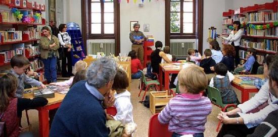 un gruppo di bambini e genitori all'interno di una biblioteca