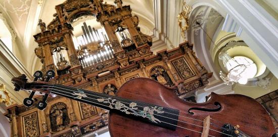 un violino in primo piano, organo di chiesa sullo sfondo