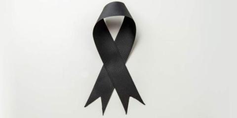 Fiocco nero al centro dell&#039;immagine su sfondo grigio, in segno di lutto