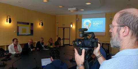 Un cameraman al lavoro durante la conferenza stampa mentre riprende i vari relatori raccolti attorno al tavolo