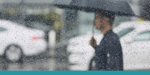 persona cammina sotto la pioggia nel traffico