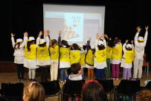 Bimbe e bimbi con cappellini e pettorine sul palco del teatro Iqbal