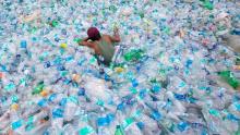 persona che nuota in un mare di bottiglie di plastica