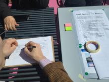 Un partecipante lascia i suoi dati; a destra un foglio con tutte le info sul progetto "Fuori dal Comune"