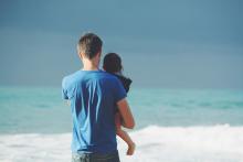 papà con bambino in braccio davanti al mare