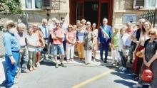 Foto di gruppo davanti al portone di via Strozzi 23 e accanto alla targa: Autorità, relatori, cittadine e cittadini