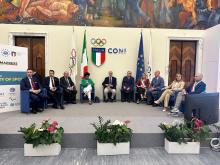 relatori seduti in semicerchio sullo sfondo bandiera CONI