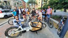 bicibus bambini e genitori: in primo piano cargo-bike per trasporto zaino e casco