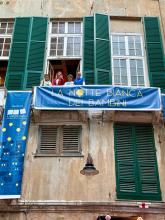Lo striscione blu "La notte bianca dei bambini" appeso a un terrazzino con Salis, Lodi e organizzatori