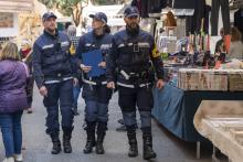 tre agenti camminano tra banchi di mercato rionale
