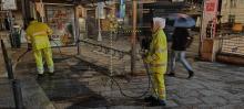 Operatori di Amiu impegnati nella pulizia del marciapiedi di una fermata AMT con l'impiego di una idropulitrice
