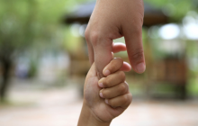 Due mani, una più grande e l'altra più piccola, che si intrecciano Due mani, una più grande e l'altra più piccola, che si intrecciano