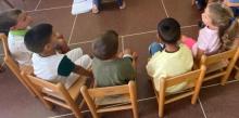 Bimbe e bimbi seduti su piccole sedie e fotografati di spalle