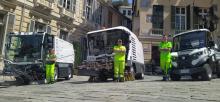 Panoramica su tre nuovi mezzi elettrici con davanti tre addetti di Amiu in posa