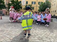 bambino di spalle con paletta e gilet giallo dìcon scritta polizia locale