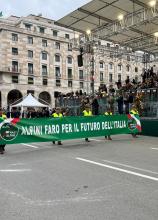 Alpini portano lo striscione con scritta bianca su sfondo verde "Alpini faro per il futuro dell'Italia"