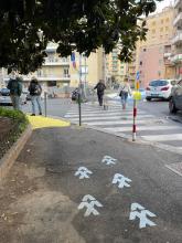 Un marciapiedi con alcune frecce che indicano il percorso Pedibus 