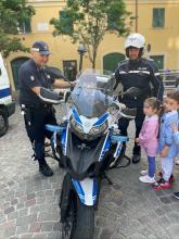 bambino a cavalcioni sulla moto e due vigili motociclisti