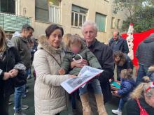 Una coppia di nonni con in braccio la nipotina e in mano calendario e giornalino scolastico