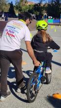 Un adulto, fotografato di spalle, aiuta una bambina ad andare in bicicletta Un adulto, fotografato di spalle, aiuta una bambina ad andare in bicicletta