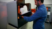 operatore estrae la copia del corpo del violino dalla stampante in 3d