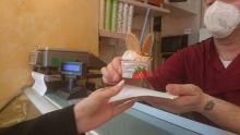 particolare del gesto del gelataio che porge un gelato