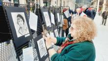 Una visitatrice della mostra fotografa uno dei 22 ritratti delle Madri Costituenti appesi all'ex mercato di corso Sardegna