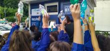 I bimbi fotografati di spalle mentre tengono in mano ciascuno una bottiglia di plastica