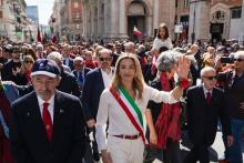 La sindaca Salis saluta i presenti in via XX Settembre durante il corteo: alla sua destra il presidente Bucci